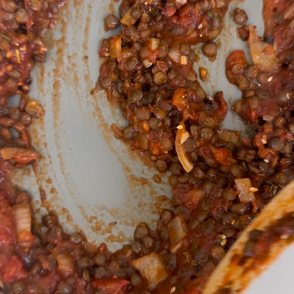 lentils, onions, tomato sauce and garlic with spices cooking in a pan