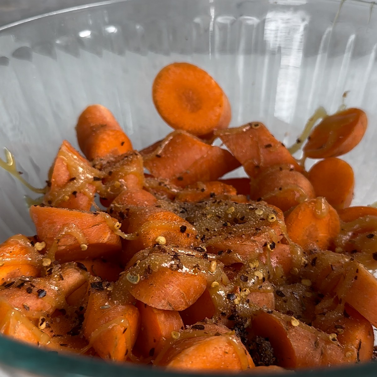 carrots in a bowl with honey, oil and spices