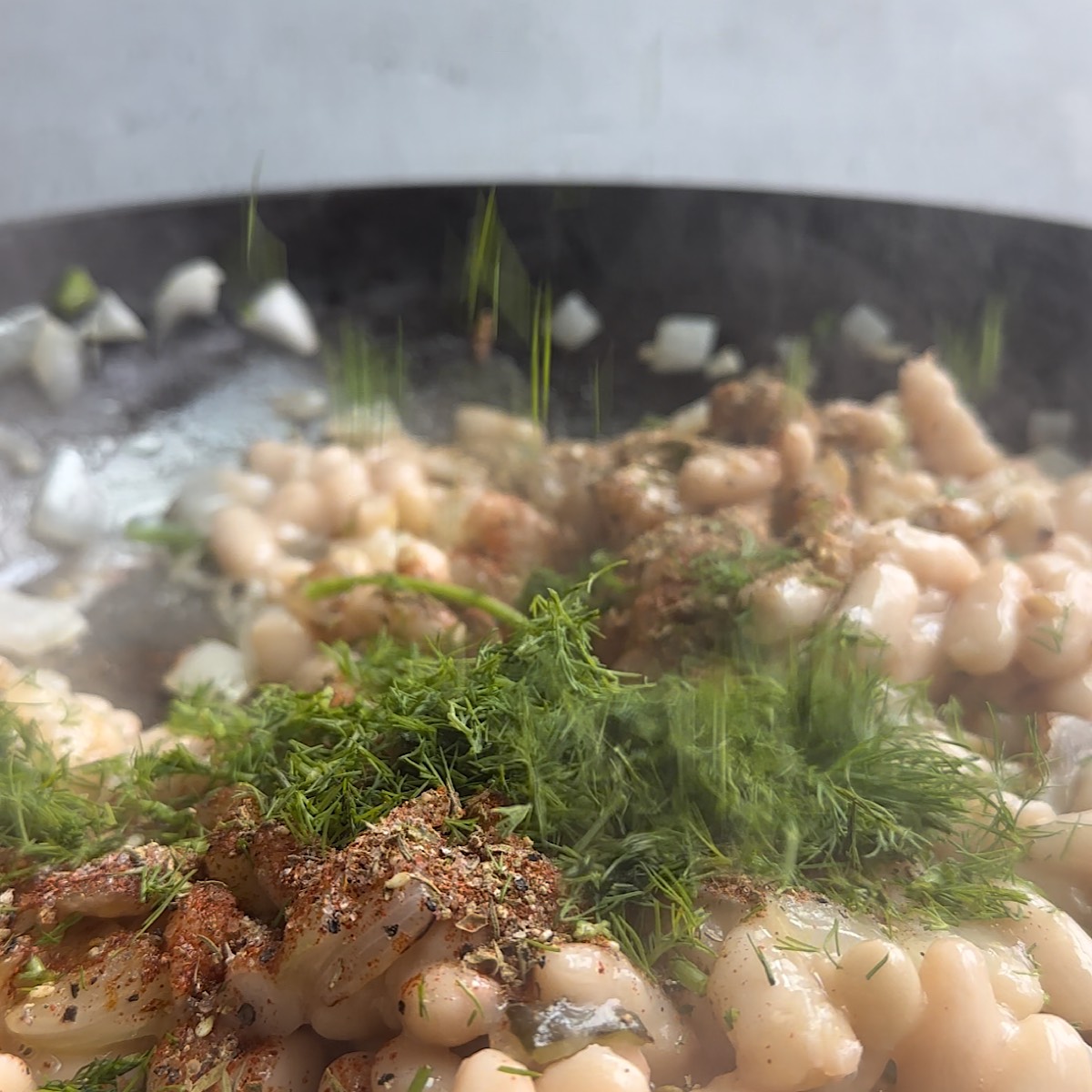 beans onions and herbs in a pan
