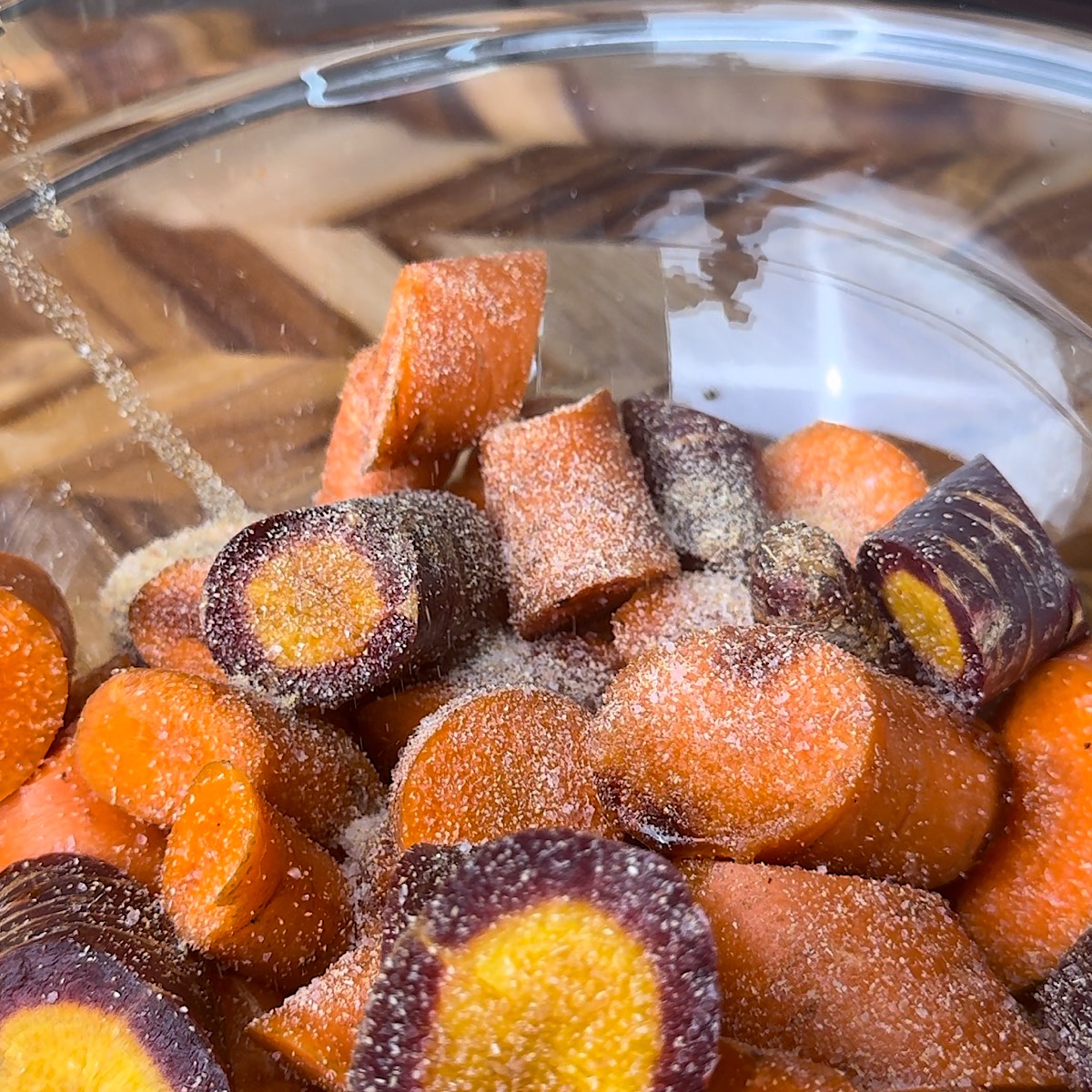 carrots in bowl with seasoning and oil.